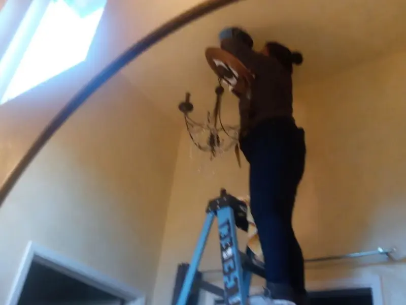 Electrician installing a chandelier in a Taneytown residence
